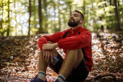 Portrait-of-relaxed-young-man-with-bluetooth-headphones-in-forest-1286401346_6720x4480